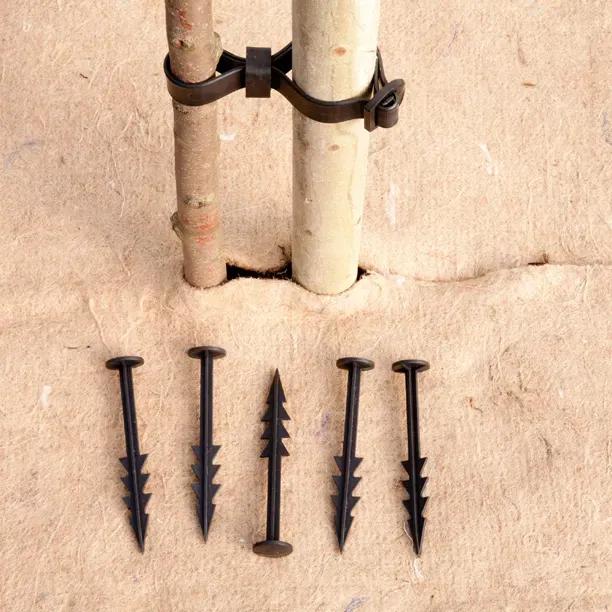 Tree Planting Pack sundries showing wooden stakes metal clamp and black plastic tree ties on sandy surface